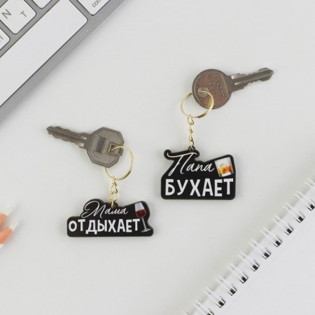 The paired key fobs “Dad Bujet/Mom Rests”, 5.2 x 7.2 cm.-1