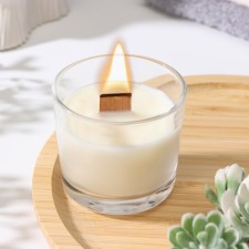 A candle made of soy wax in a glass with a wooden wick 