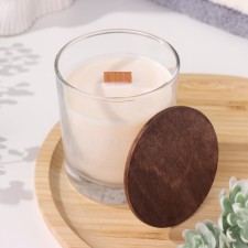 A candle made of soy wax in a glass with a wooden wick and a lid 