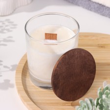 A candle made of soy wax in a glass with a wooden wick and cover 