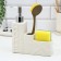 A dispenser for liquid soap with a sponge and a brush for dishes, white, 16 x 12 x 4 cm.