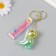 A plastic keychain with a carbine, a dinosaurus strap is green 2.5x5x5x5 cm