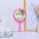 A mirror with a handle, bilateral, with an increase, D mirror surface 12.5 cm, pink color