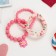 The kit of children's “chosen” 3 objects: elastic band, 2 bracelets, flower, pink matte color