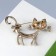 Brooch "Cat" flirty with a bow, the color is white in coffee gold