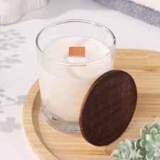 A candle made of soy wax in a glass with a wooden wick and lid 