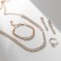 Set 4 objects: earrings, necklaces, bracelet, ovala ovals ring, white color in gold