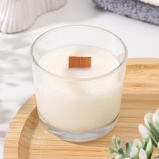 A candle made of soy wax in a glass with a wooden wick 