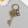 A keychain metal, glass "Castle with a heart and a key with roses" bronze 10 cm