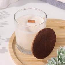 A candle made of soy wax in a glass with a wooden wick and a lid 