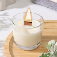A candle made of soy wax in a glass with a wooden wick 