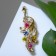 Brooch "Firebird", tail with flowers, colored in gold
