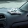 Toy on a car panel, a dog on a pillow, white and black color