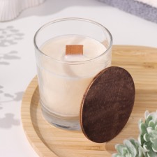 A candle made of soy wax in a glass with a wooden wick and cover 