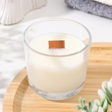 A candle made of soy wax in a glass with a wooden wick 