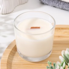 A candle made of soy wax in a glass with a wooden wick 
