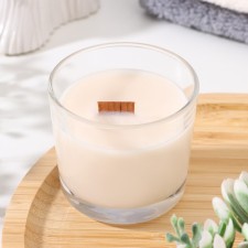 A candle made of soy wax in a glass with a wooden wick 