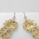Earrings with rhinestones "flowers" bends, white color in gold