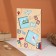 A postcard with a wooden element "fly away!"