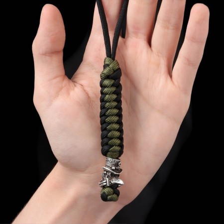 A keychain is a label for a “plague doctor” knife from a paracord, black and green