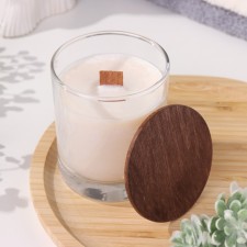 A candle made of soy wax in a glass with a wooden wick and lid 