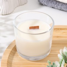 A candle made of soy wax in a glass with a wooden wick 