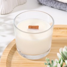 A candle made of soy wax in a glass with a wooden wick 