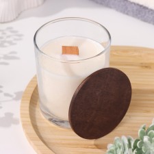 A candle made of soy wax in a glass with a wooden wick and cover 