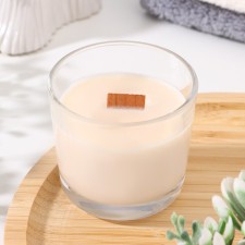 A candle made of soy wax in a glass with a wooden wick 