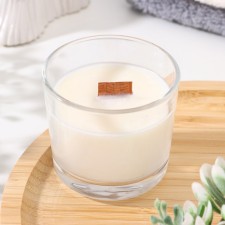 A candle made of soy wax in a glass with a wooden wick 